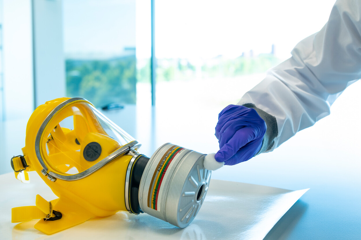 Onderzoeker neem gasmasker af met watje 