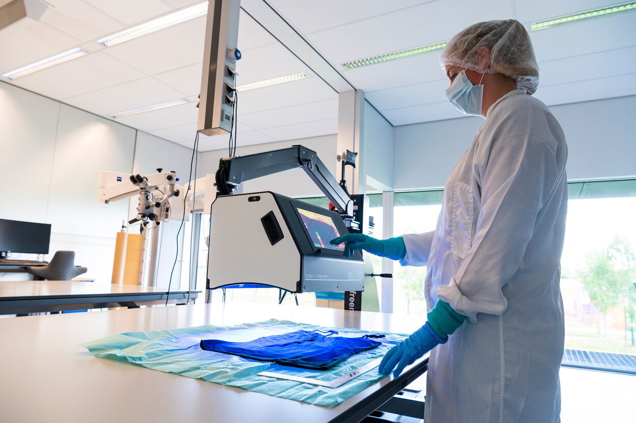 Onderzoeker gebruikt forensisch licht om biologische sporen op een shirt te vinden