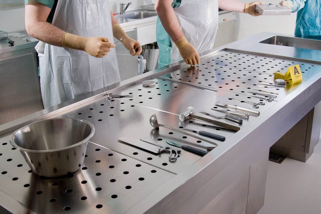 Forensische pathologen staan om een sectietafel