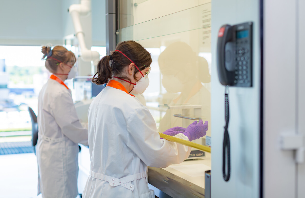 Onderzoeker bekijkt groene pil in zuurkast op lab