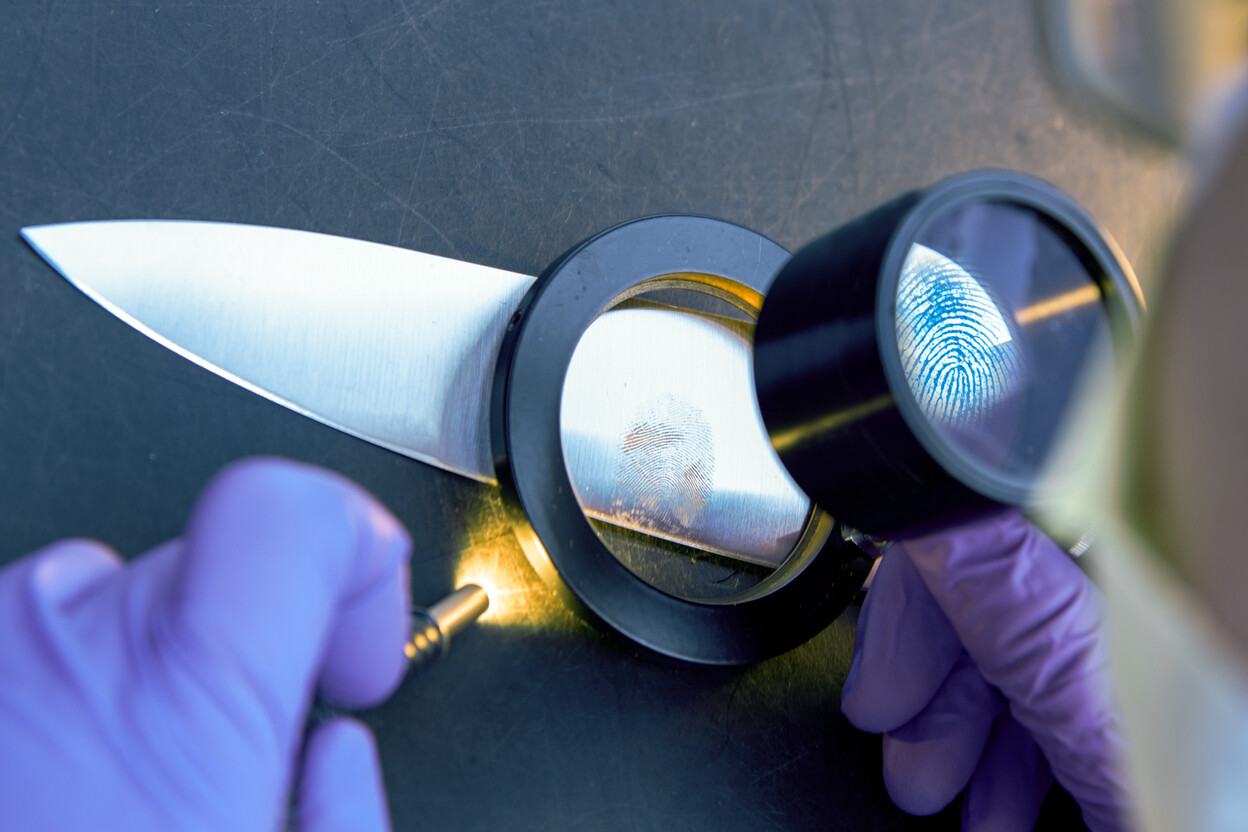 Deskundige bekijkt vingerspoor achtergelaten op het lemmet van een mes