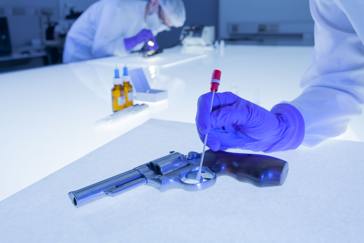 Onderzoeker gebruikt wattenstaafje op revolver om DNA sporen te vinden
