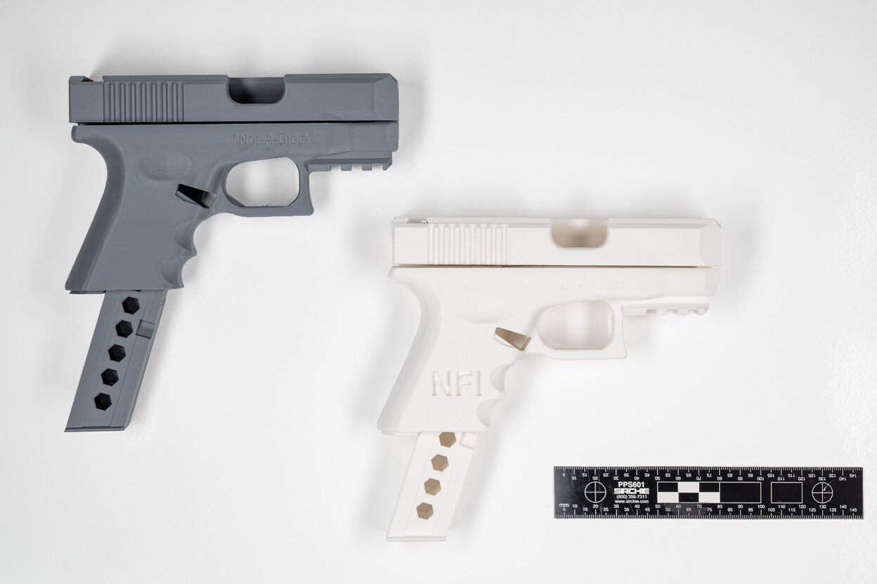 Twee 3D geprinte handvuurwapens met liniaal op witte tafel