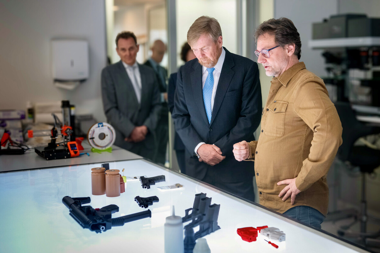 Koning Willem-Alexander bekijkt met wapendeskundige diverse wapens op een tafel