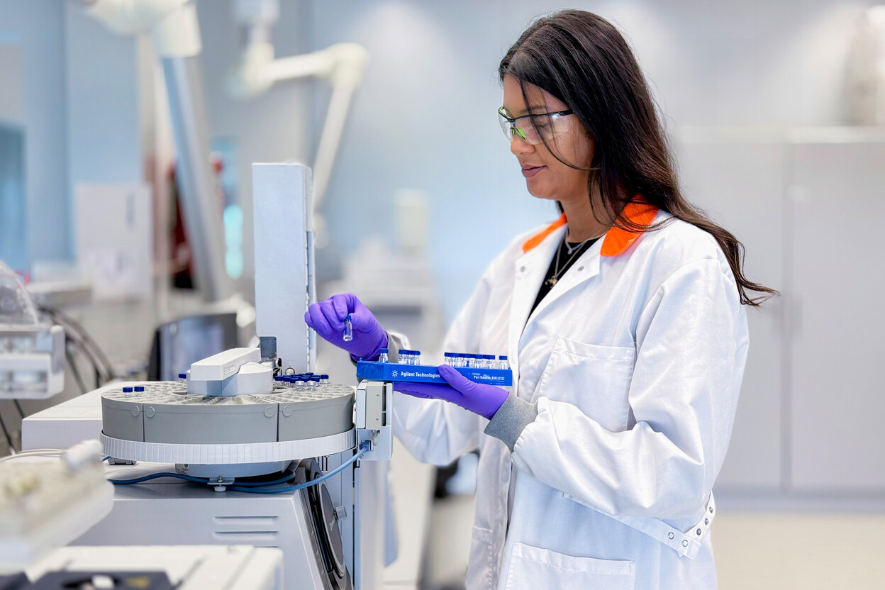 Onderzoeker op laboratorium plaatst glazen vaatjes in apparatuur