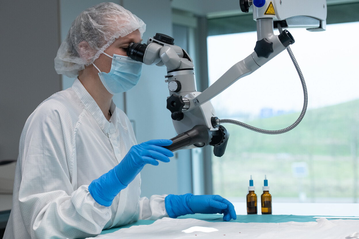 Onderzoeker bekijkt kledingstuk door microscoop