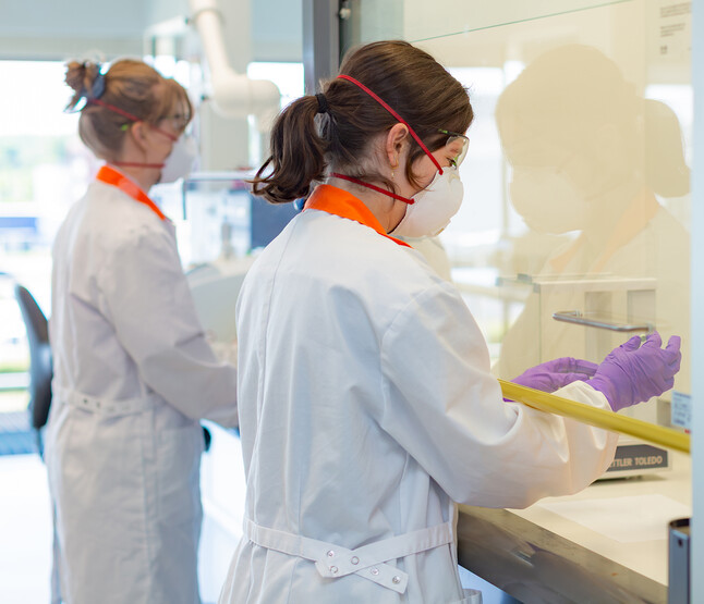 Onderzoeker bekijkt groene pil in zuurkast op lab